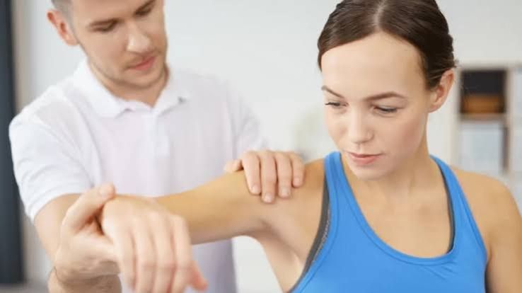 Fisioterapeuta fazendo teste manual de força no braço da paciente